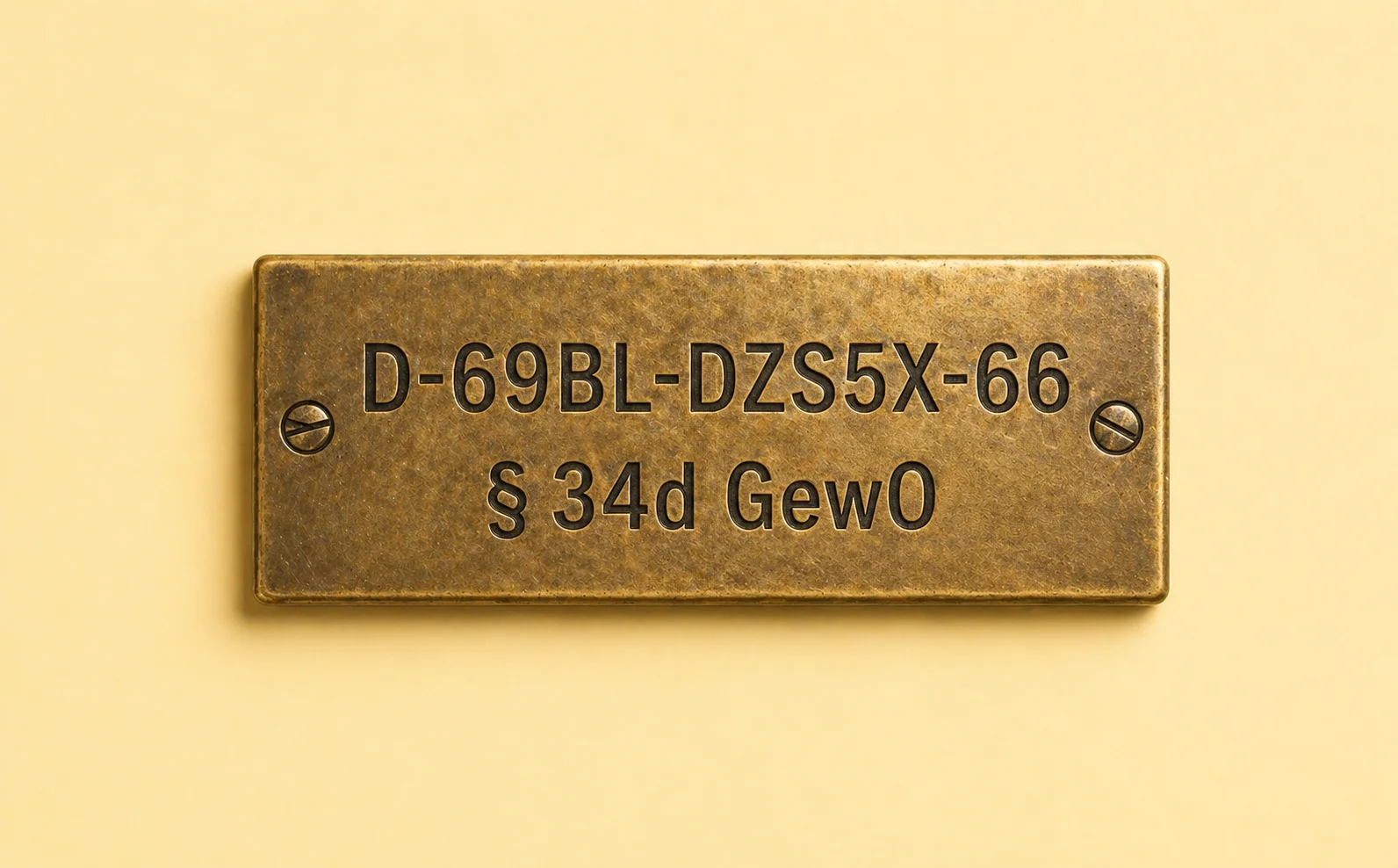 Detail einer messingbeschlagenen Vermittlerregister-Plakette vor pastell-buttercreme-farbenem Studio-Hintergrund. Eingraviert sind die IHK-Nummer D-69BL-DZS5X-66 und § 34d GewO.